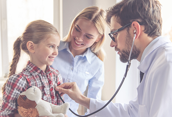 little girl getting heart checked with mom and doctor